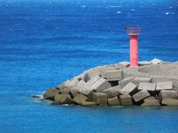 distant view of a red lighthouse on an island in gran canaria