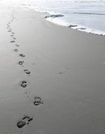 footprints of a man on the gray sand on the coastline