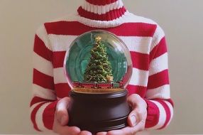 glass Globe with Christmas tree inside in male hands