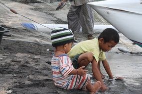 children play near fishing boats