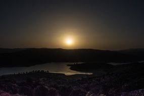 sun in the sky over the lake at dusk