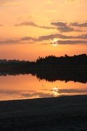 pink sunset and black forest reflected in the lake