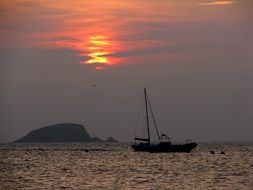 fishing boat on sea in view of rock at Sunset, uk, scotland