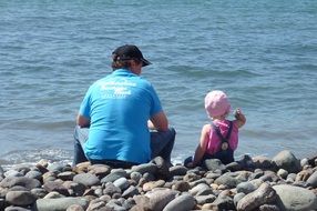 dad with a child on a stone beach
