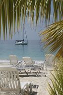 sunbeds on a sandy beach and a sailing ship at sea