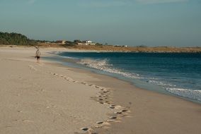 man walks along the beach in Galicia, Spain