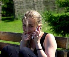 girl is talking on the phone on a bench