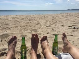 bottles of beer between your feet on the sand on the beach