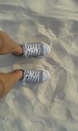 feet in light shoes on the sand