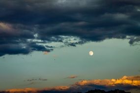 moon in the sky near dark clouds