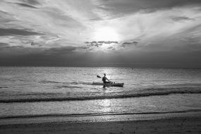 man on a boat kayak at sunset black white photo