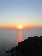 sunset on the horizon over the coast of greece