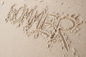 sommer, inscription summer in german on wet sand beach