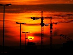 construction cranes at red sunset