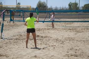 vacationers play beach tennis