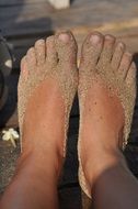 human feet in the sand in summer