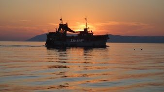 sunset over a ship in calm water