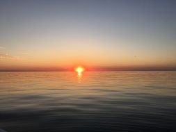 the setting sun over the horizon of the lake