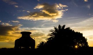 silhouette of pavilion beside of palms at sunset sky