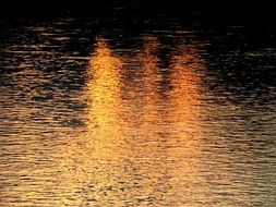 three golden stripes on the surface of the water from the evening sun