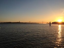 distant view of the bridge in Lisbon at colorful sunset on horizon