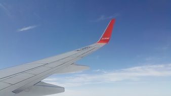 wing of a red and white flying plane in flight