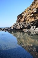 blue sky reflected in the water near the rocks