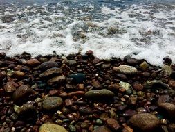 wet pebbles on the beach, sea foam