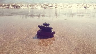 small stone tower on the wet sand of the surf
