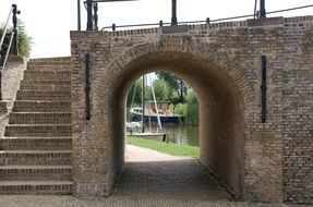 arch in the castle wall and a river and a boat