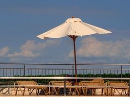 white umbrella over sun loungers on a sunny day