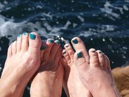 two pairs of feet by the sea