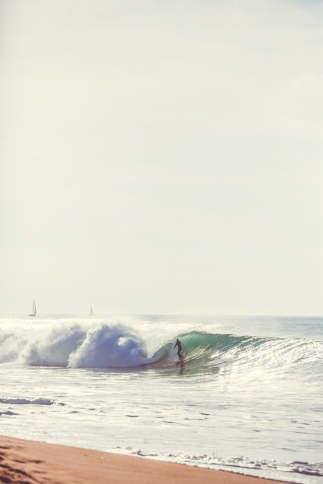 surfer on the wave on the shore of a paradise island