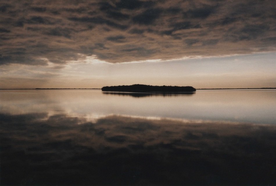 island in the ocean under dark clouds