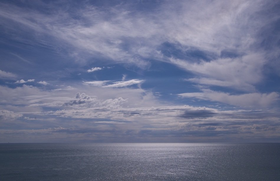white clouds in the sky above the sea