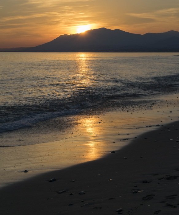 the sun over the mountain near the ocean