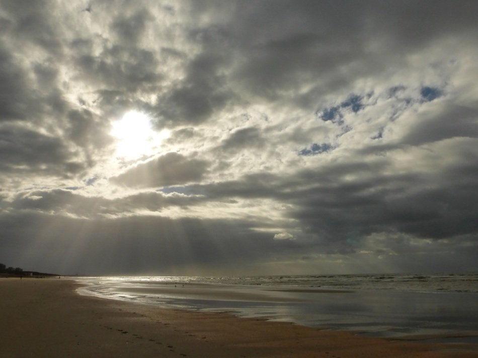 sunbeams in gray clouds over the Belgian coast