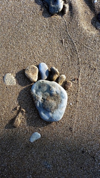 stones in the shape of a man’s footprint on a beach in Italy