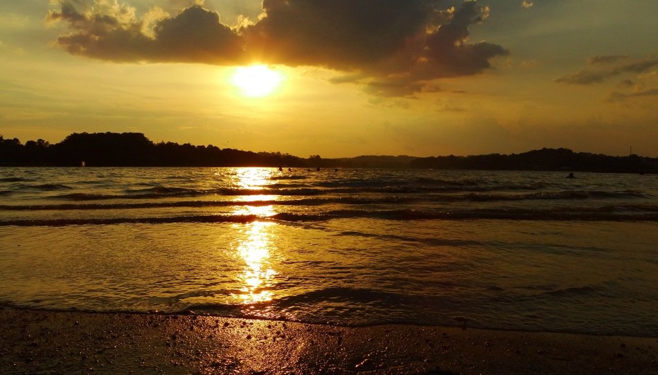 the sun in the distance by the clouds by the sea