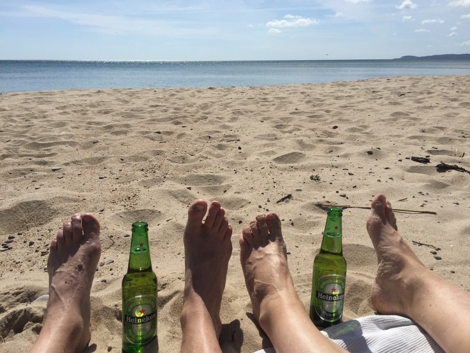 bottles of beer between your feet on the sand on the beach