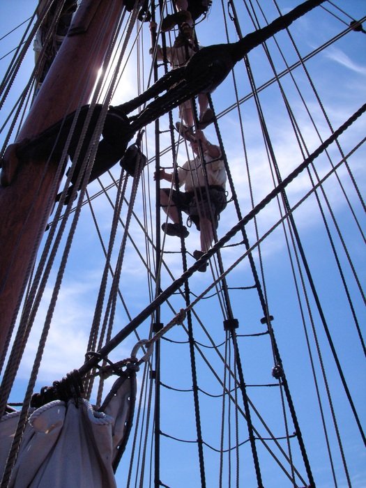 man crawling up the sailing ropes