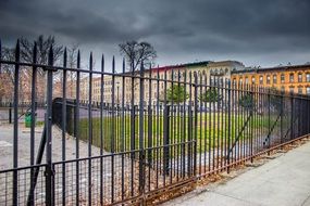 metal fence with gate under stormy clouds, usa, new york city, brooklyn