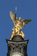 view from below of golden statue of angel of peace in Munich