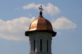the golden spire of the church on a background of clouds