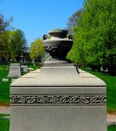 monument with stone vase on cemetery at summer