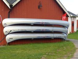 three canoes at wall of brown building