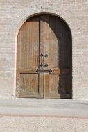 weathered arched wooden door in stone wall