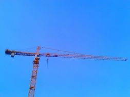 long arrow of a construction crane against the blue sky