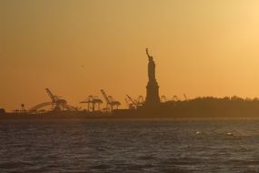 silhouette of the statue of liberty in america on sunset background