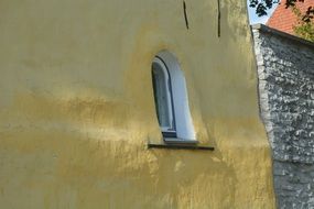 small arched window on the facade of a yellow building